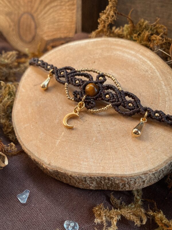 Collier ras de cou en micro macramé avec petites feuilles en dessous. Perles dorées, petite Lune en pendentif en dessous. Perle en pierre d'oeil de tigre en centre. Breloques gouttes sur les côtés.