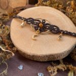 Collier ras de cou en micro macramé avec petites feuilles en dessous. Perles dorées, petite Lune en pendentif en dessous. Perle en pierre d'oeil de tigre en centre. Breloques gouttes sur les côtés.